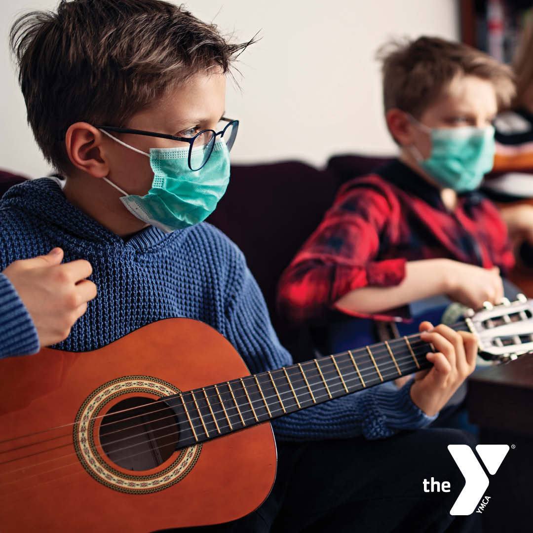 Two youth playing guitars while wearing masks
