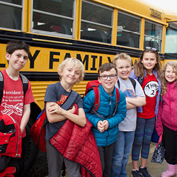 Group of youth standing outside a Treasure Valley YMCA school bus